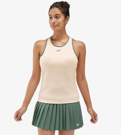 模特兒穿著 Yonex 20757 杏色女裝運動背心配襯綠色滾邊及百褶裙。 | Woman wearing a peach-colored Yonex 20757 Women's Tank Top with green trim and a matching pleated green skirt.
